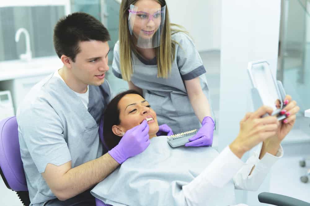 Woman in a Dentist office choosing color of her veneers